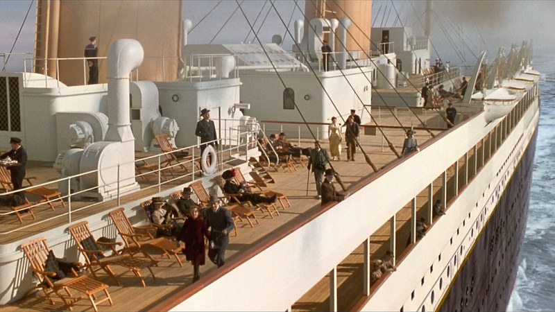 A wide shot of the Titanic at sea with passengers on deck.