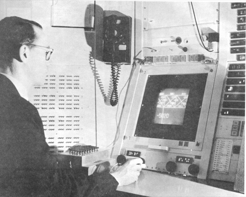 Ivan Sutherland seated at the TX-2 console operating Sketchpad, holding the light pen to the round display.